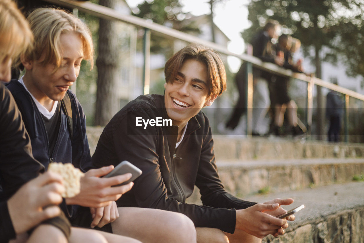 Cheerful teenage boys sitting with smart phones