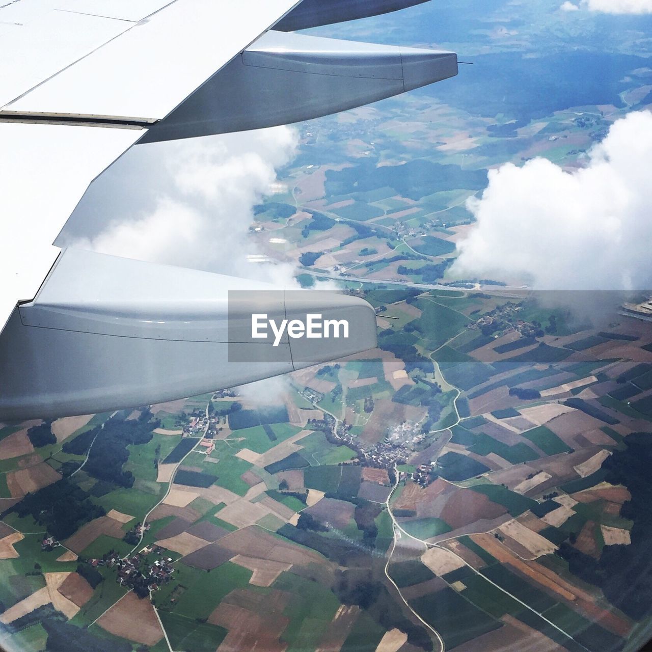 Cropped image of aircraft wing over landscape seen through window