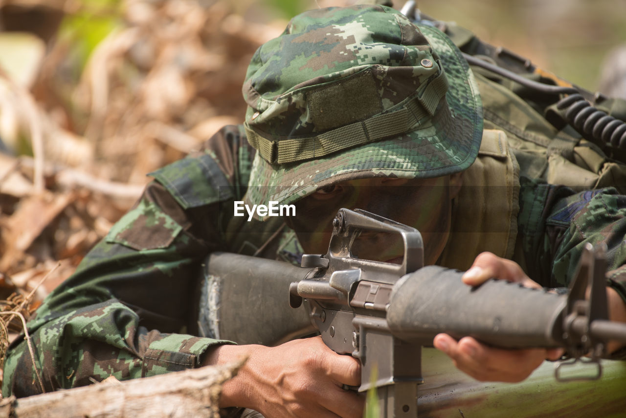 View of soldier holding rifle standing outdoors