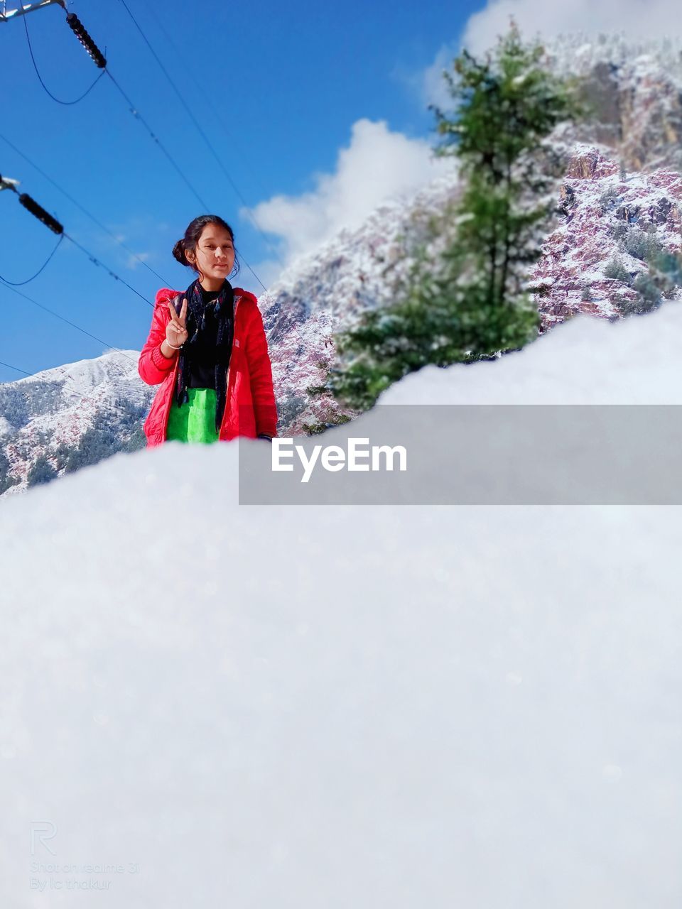 Portrait of girl standing in snow against sky