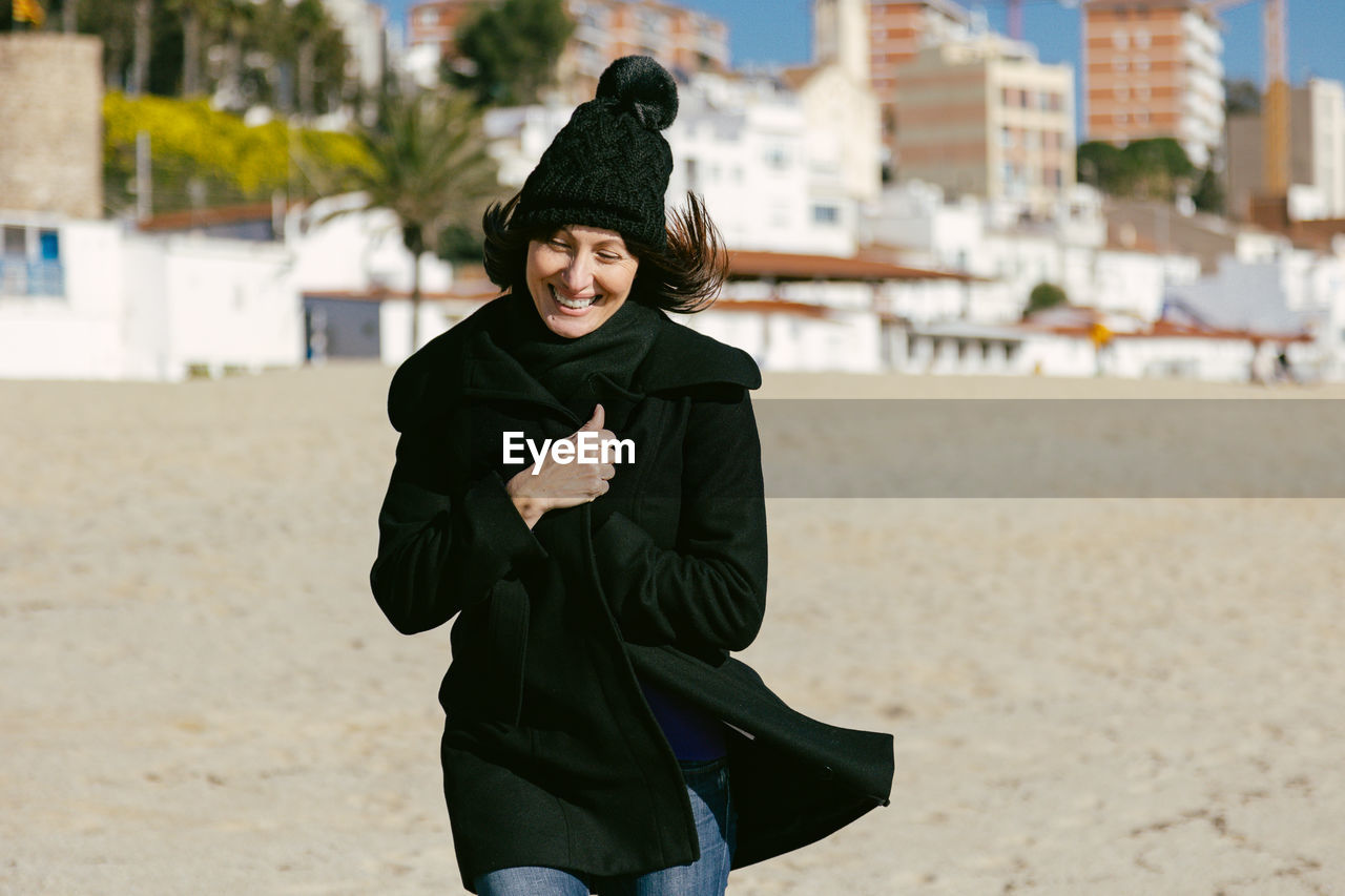 Middle-aged woman running happily along the beach on a sunny winter day