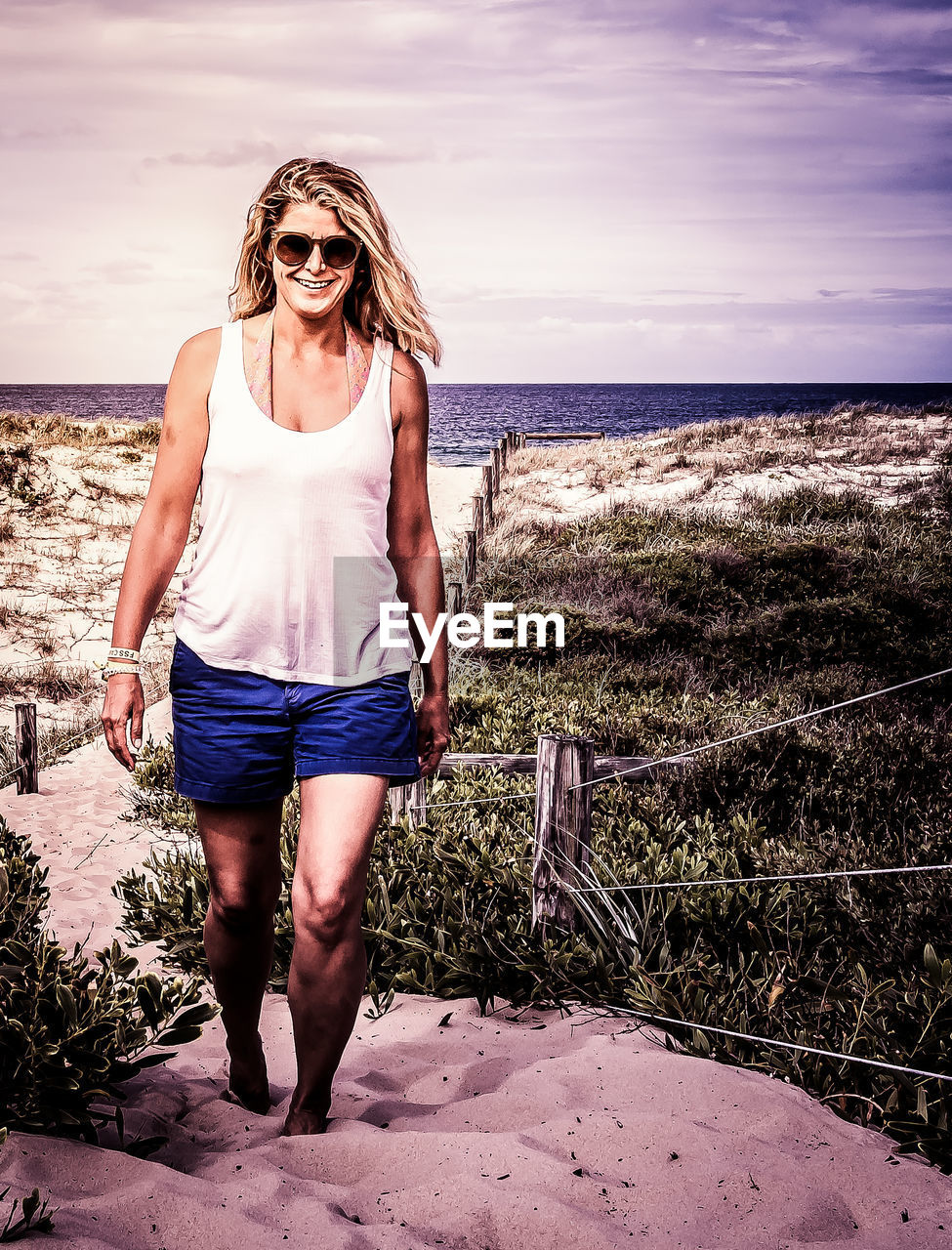 Woman walking at beach against sky