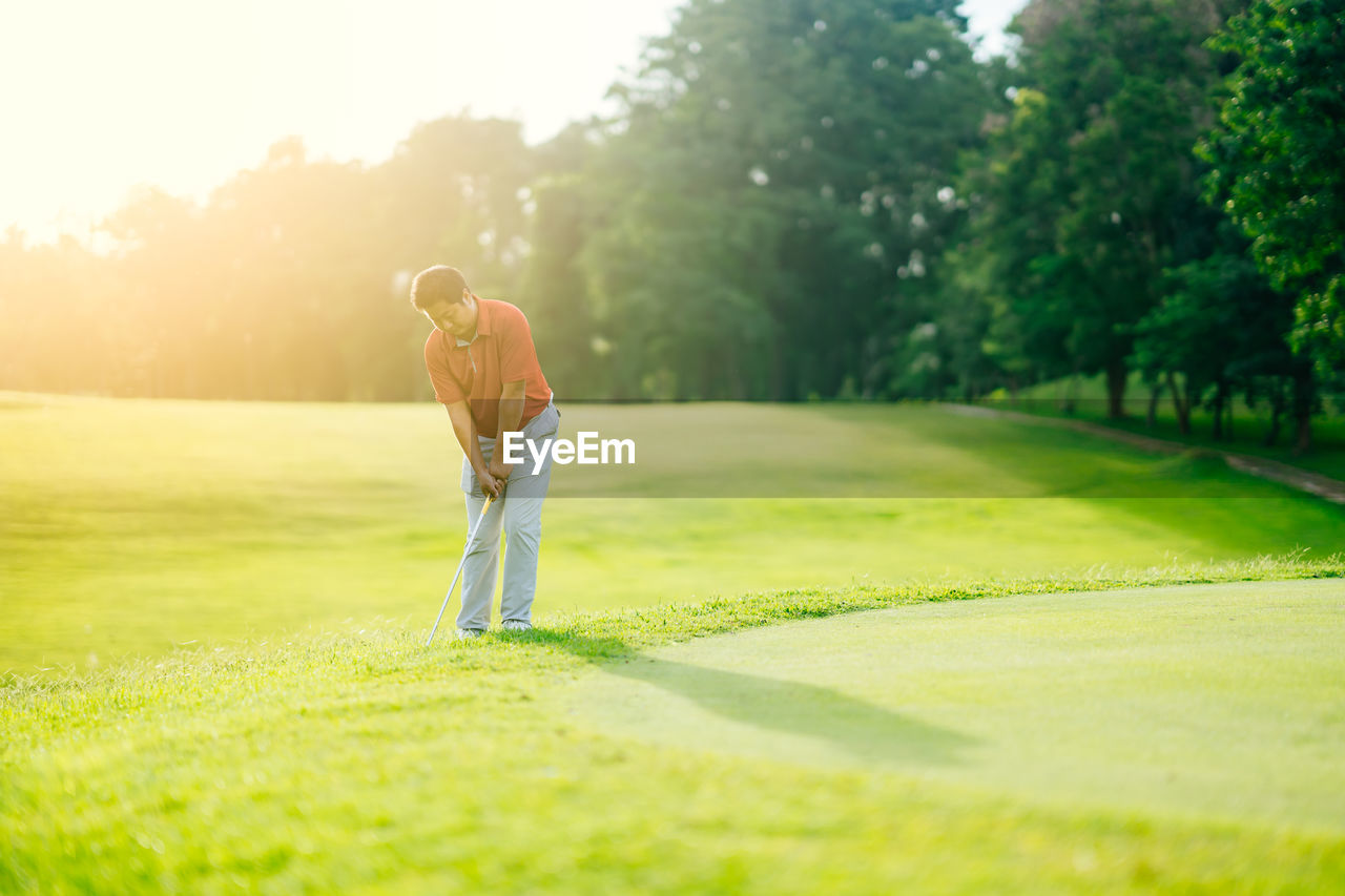 MAN CLIMBING ON GOLF COURSE