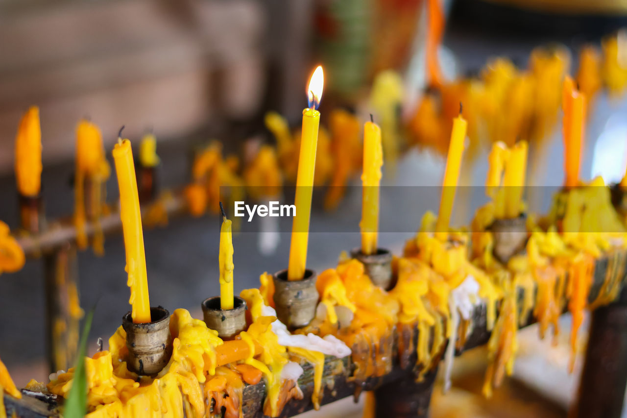 Close-up of yellow candles in temple