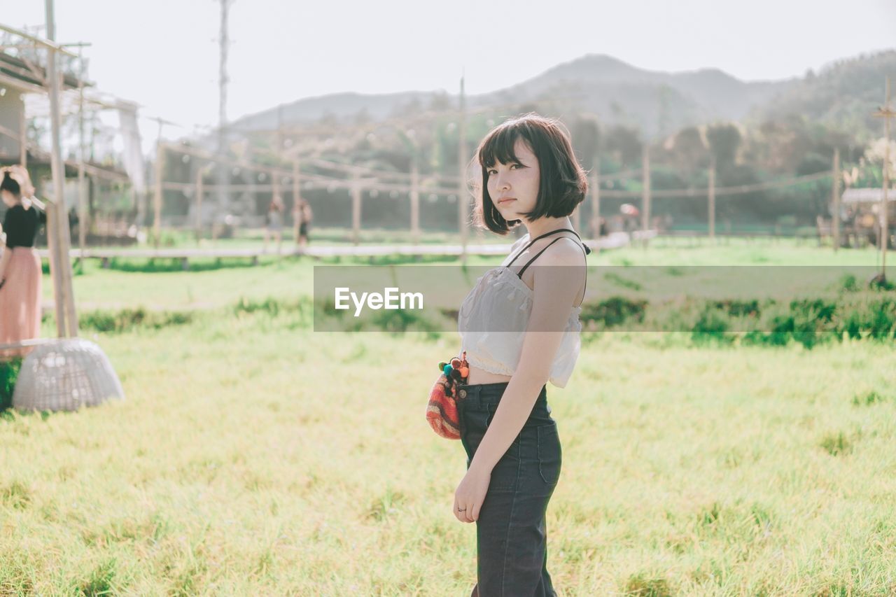 Side view of young woman standing on field