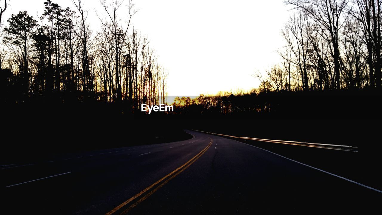 EMPTY ROAD WITH TREES IN BACKGROUND