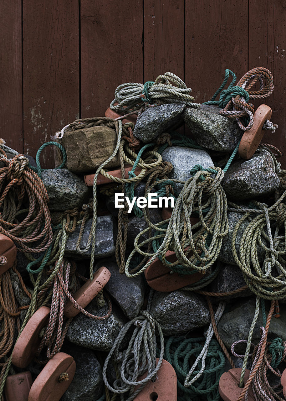 CLOSE-UP OF FISHING NET HANGING ON ROPE AGAINST WALL
