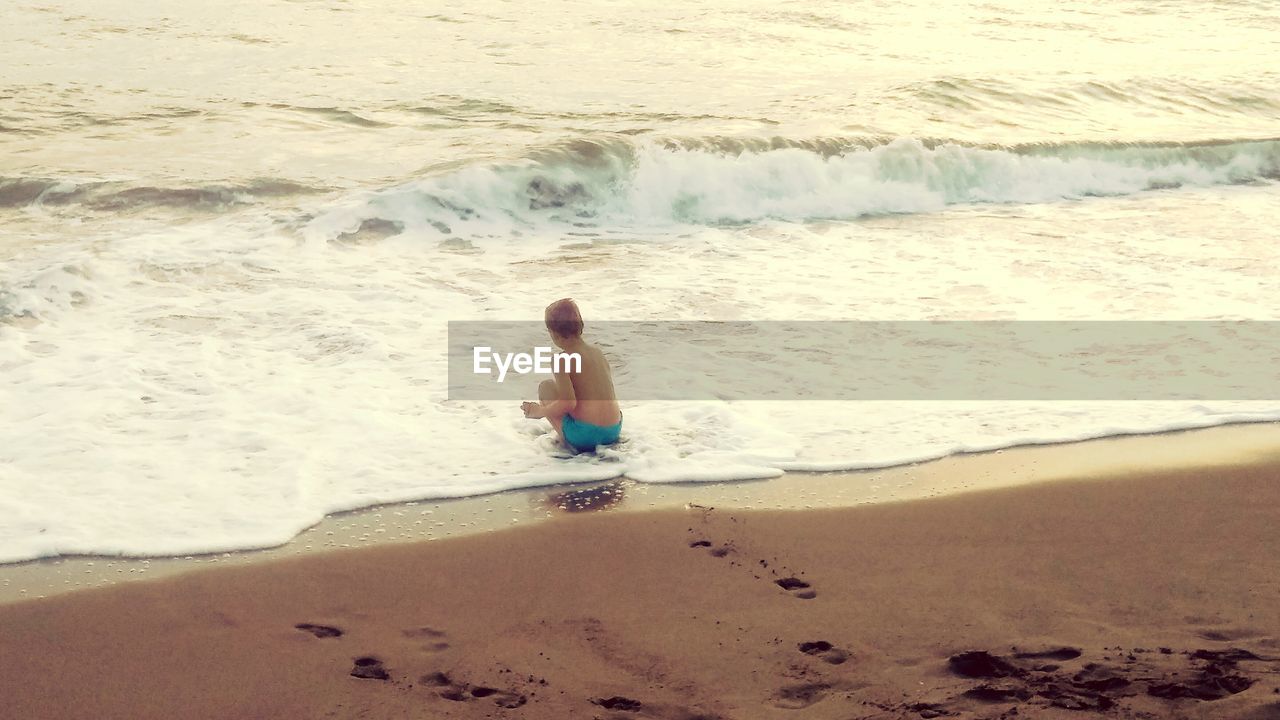 REAR VIEW OF BOY ON SHORE AT BEACH