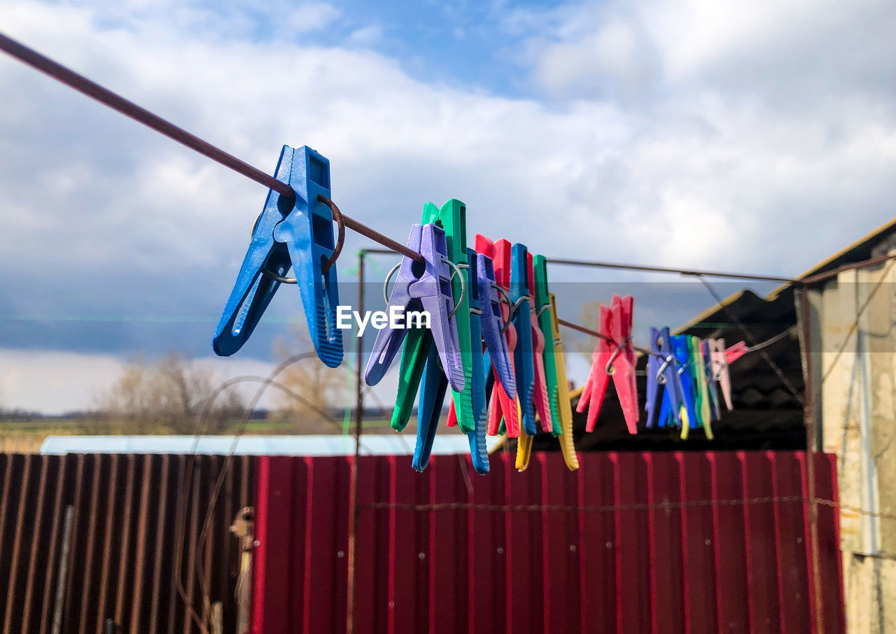 Clothespins on clothesline against sky