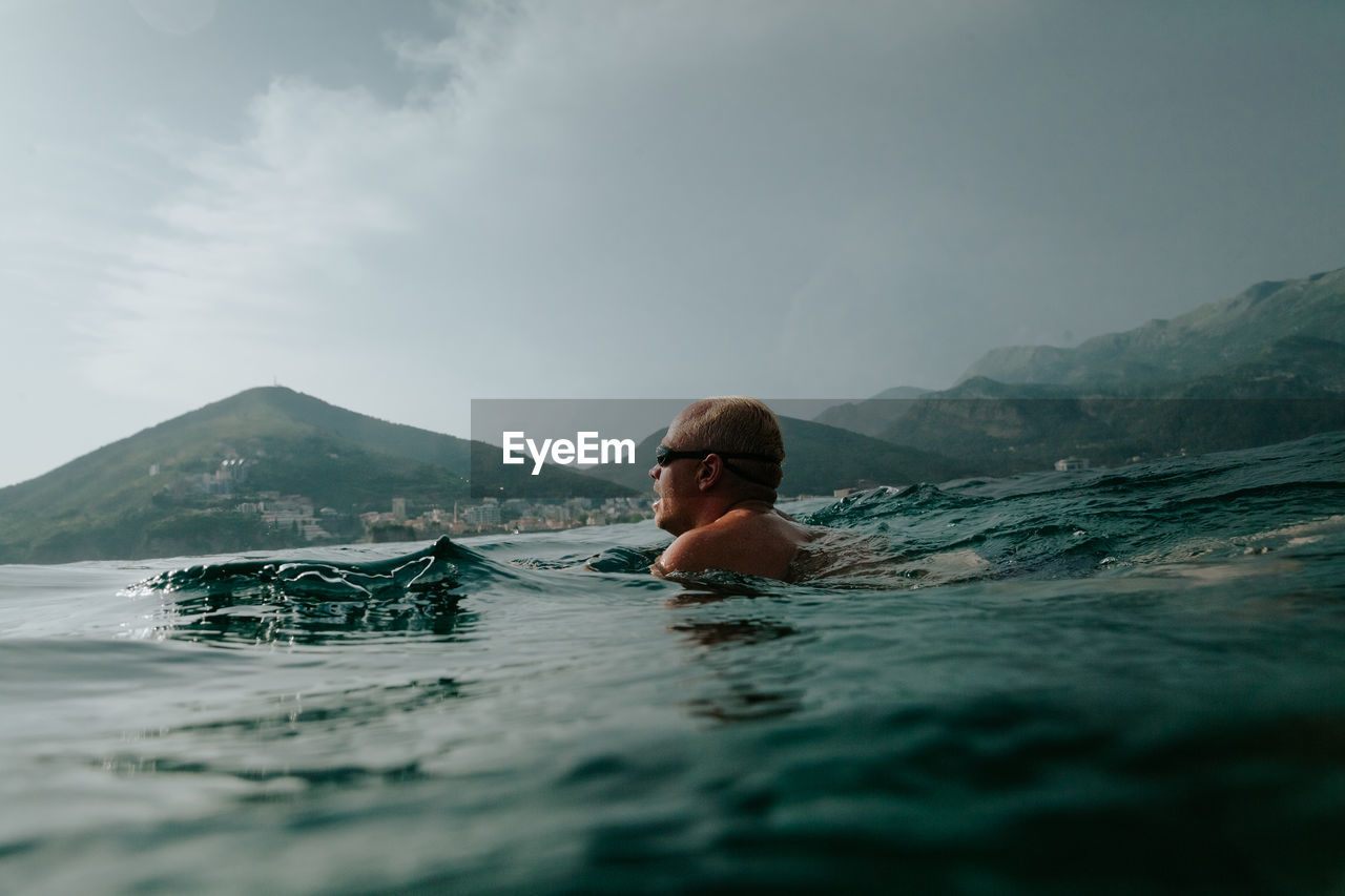 Man swimming in infinity pool against sky