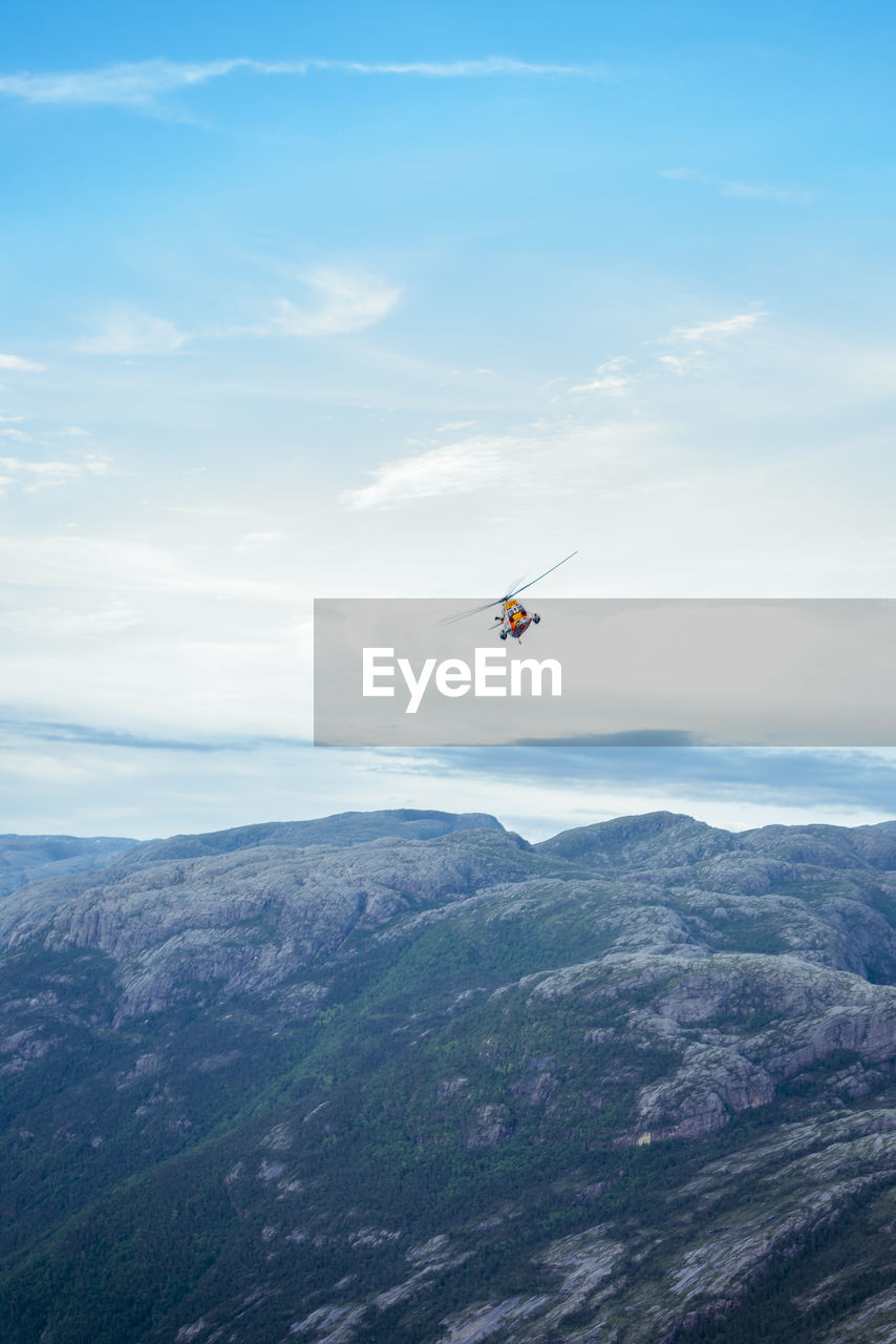 Low angle view of helicopter flying above mountains