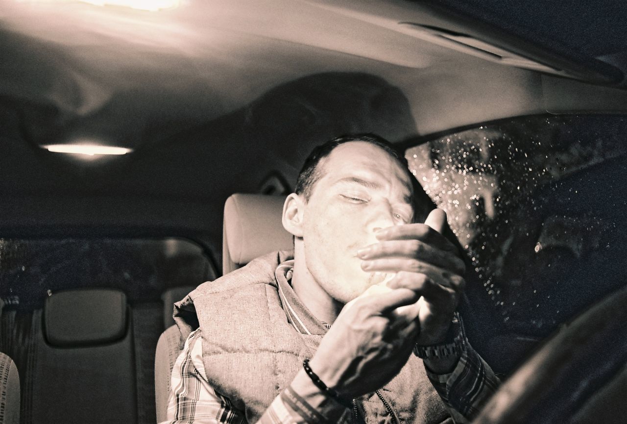 Man lighting cigarette in car at night