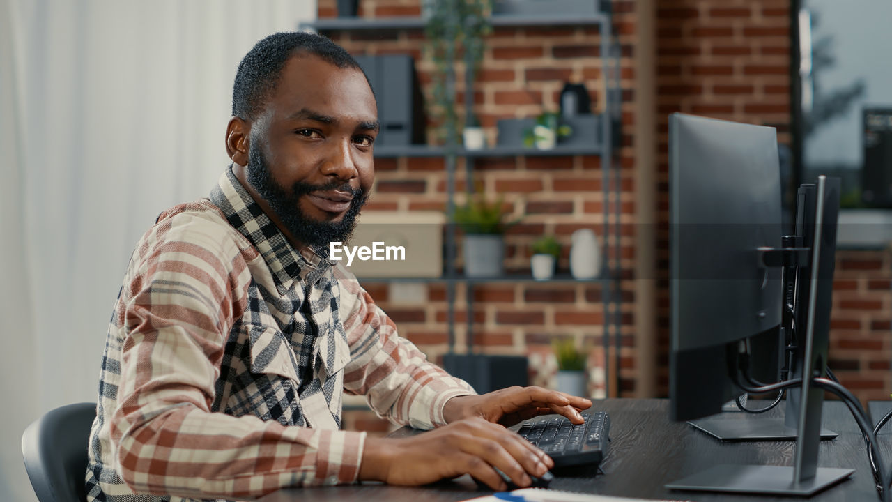 Portrait of young man using laptop while sitting on table