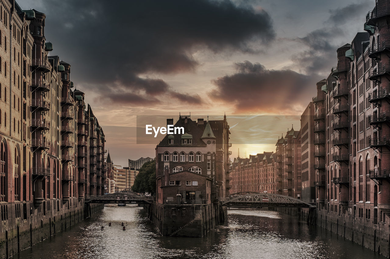 Canal amidst buildings against sky during sunset