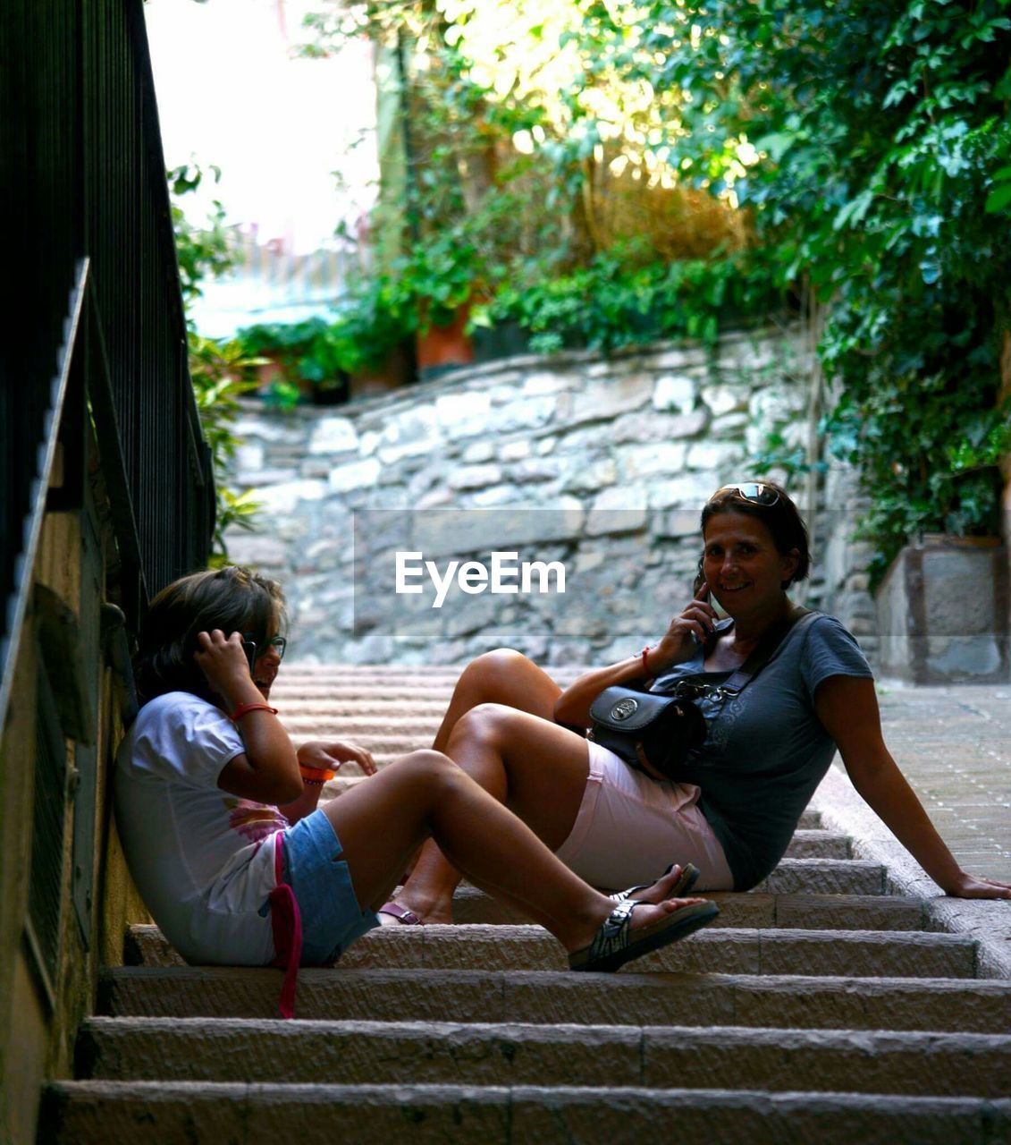 Mother with daughter talking on phone at steps