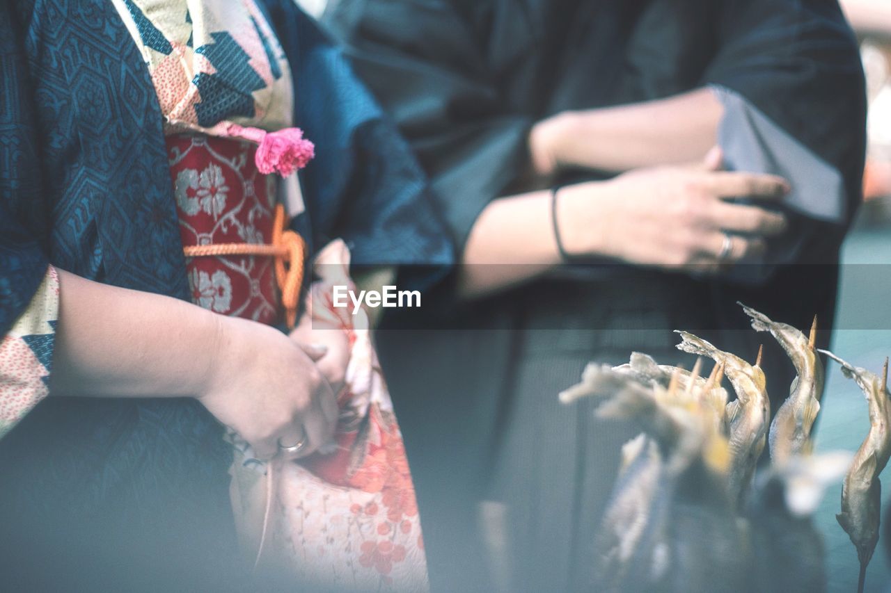 Midsection of people wearing traditional clothing while standing fish in market