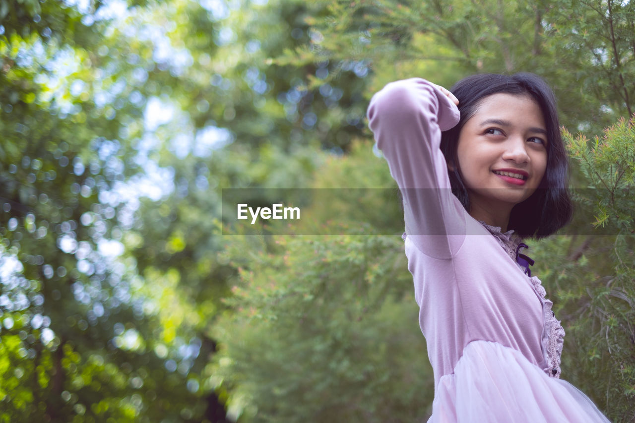 Close-up of smiling girl sitting against tree outdoors