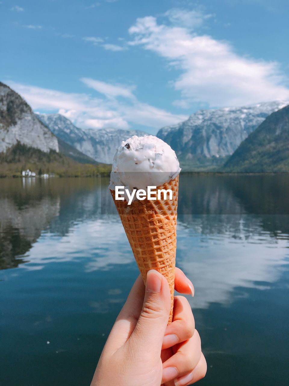 Close-up of hand holding ice cream against lake