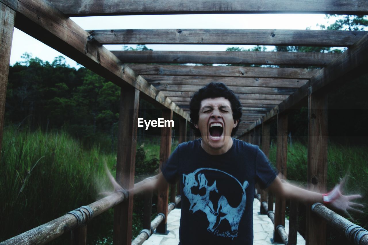 Young man shouting while standing on footbridge