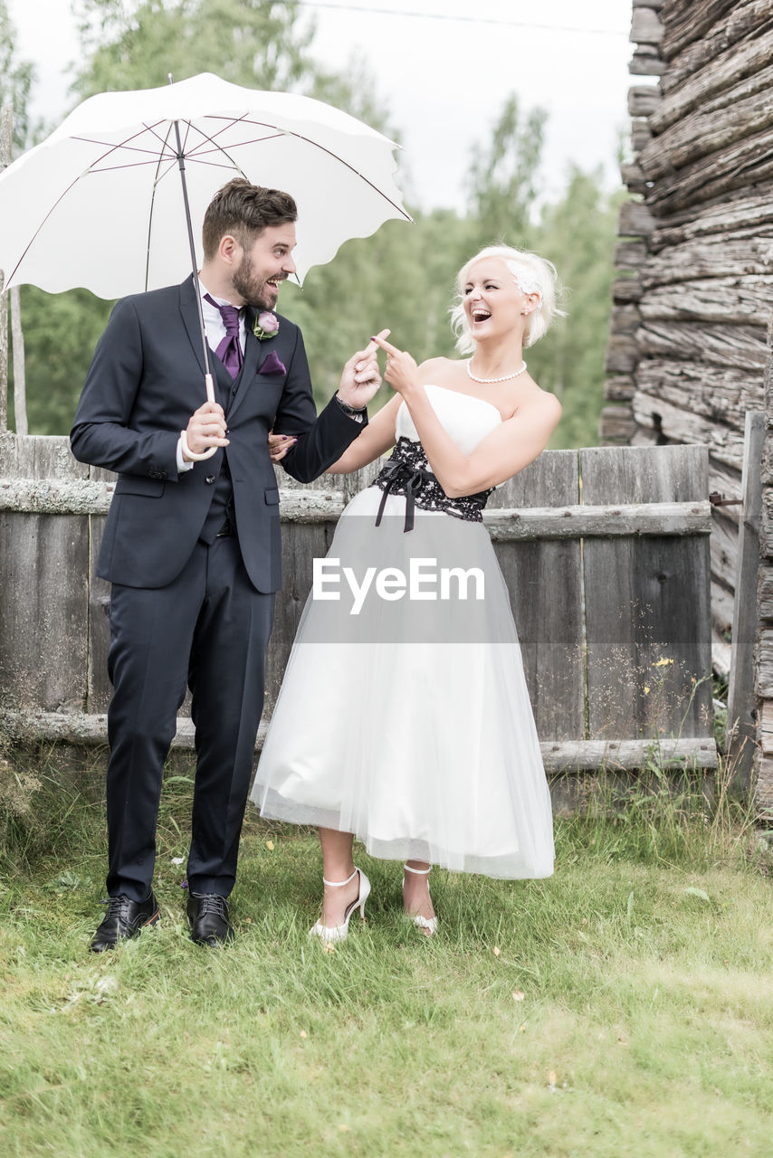 Smiling couple with umbrella standing on lawn