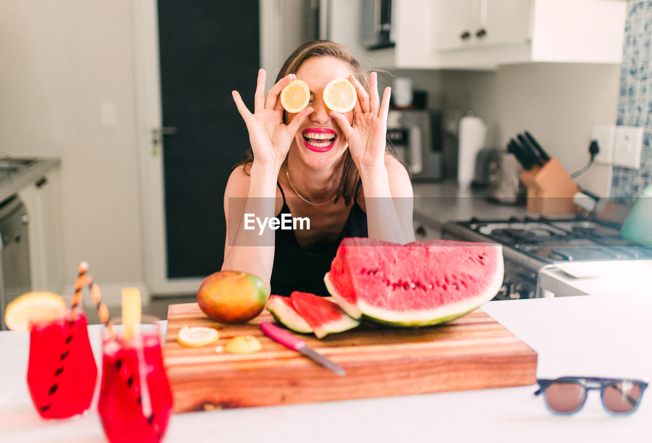 Smiling young woman with fruits on table at home