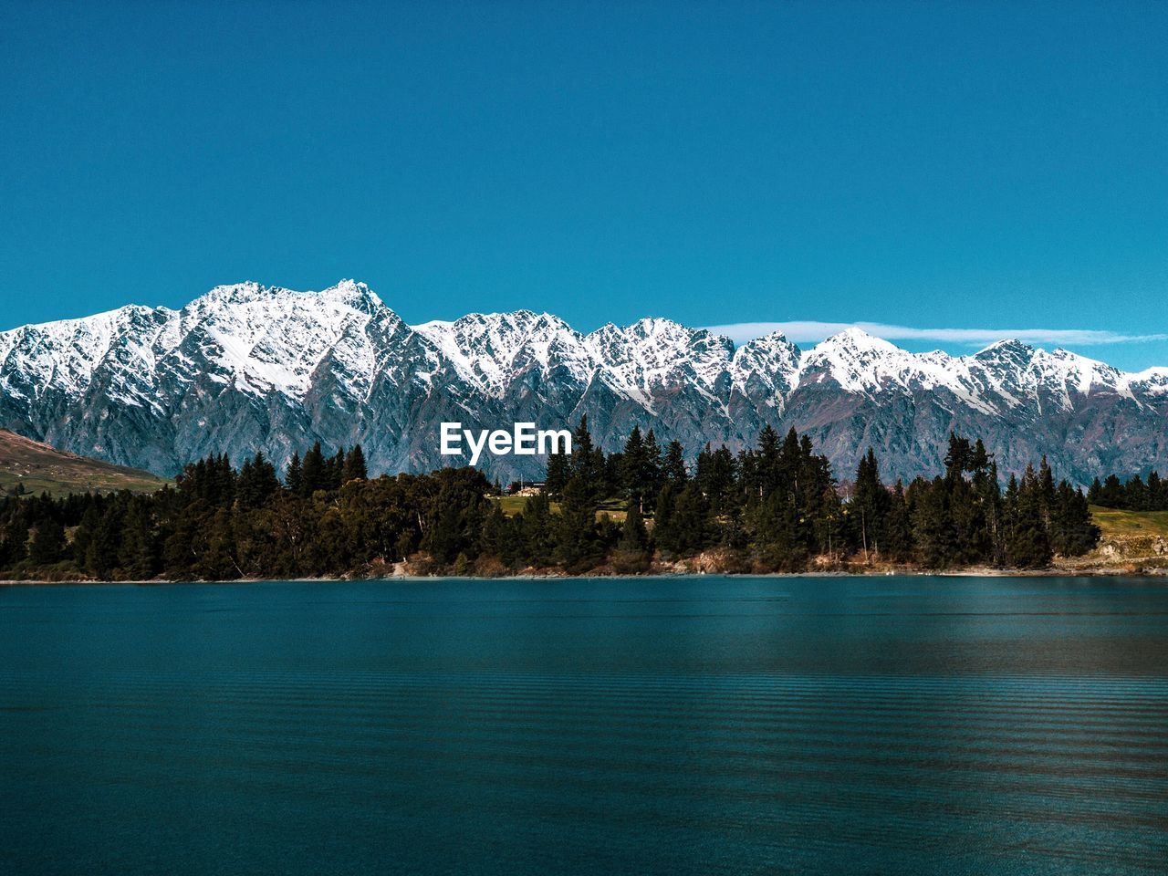 Scenic view of lake by snowcapped mountains against sky