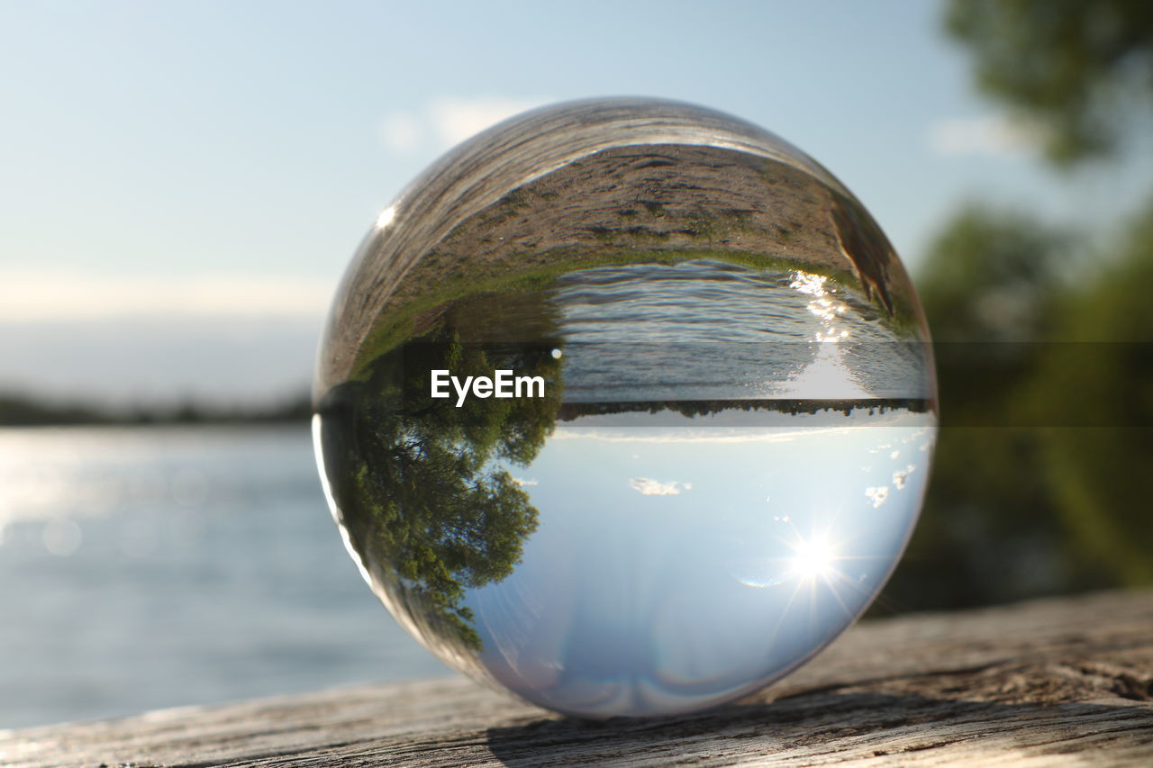 CLOSE-UP OF CRYSTAL BALL ON WOODEN POST