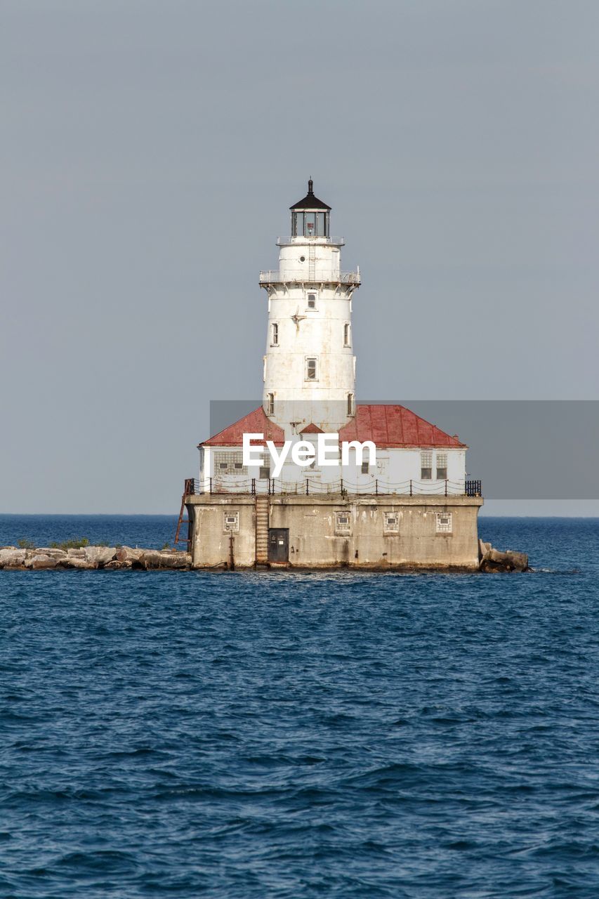 Lighthouse by sea against sky