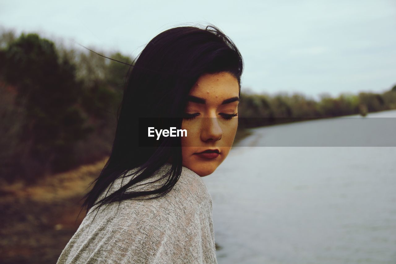 PORTRAIT OF YOUNG WOMAN AGAINST SKY