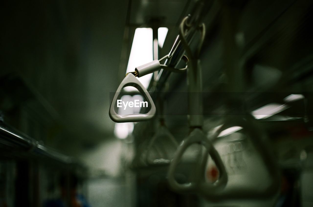 Close-up of handles hanging in illuminated train