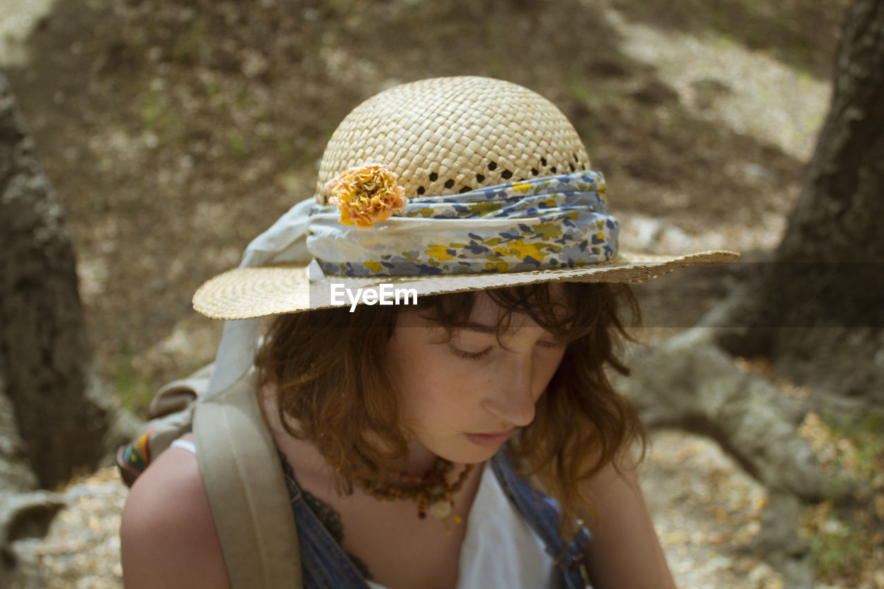 High angle view of sad young woman wearing hat in forest