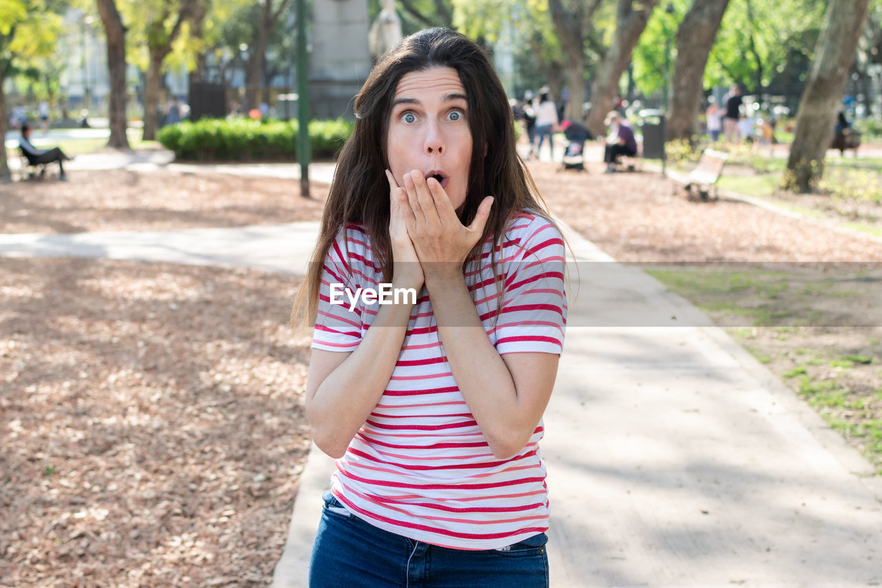 Portrait of woman making face while standing at park