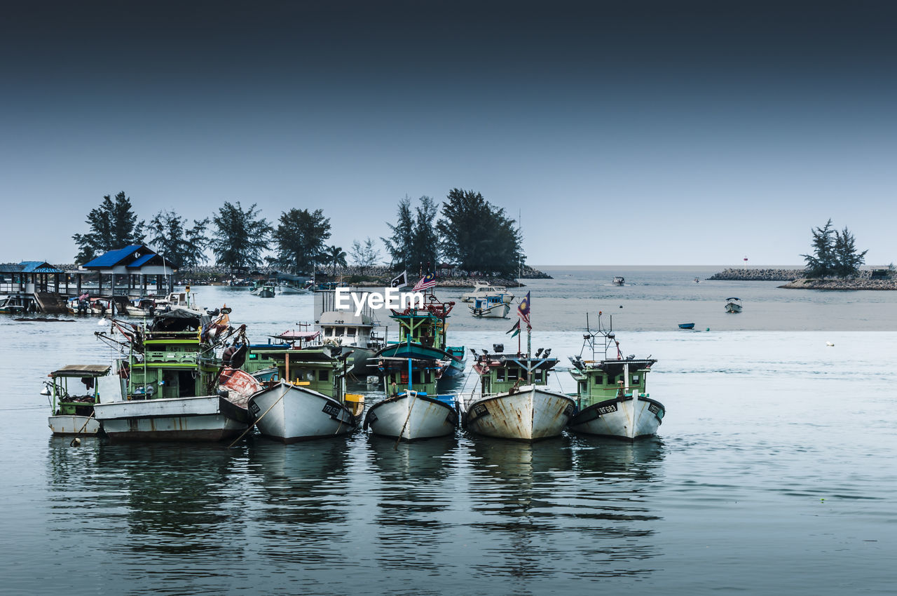 Boats moored on river against clear sky