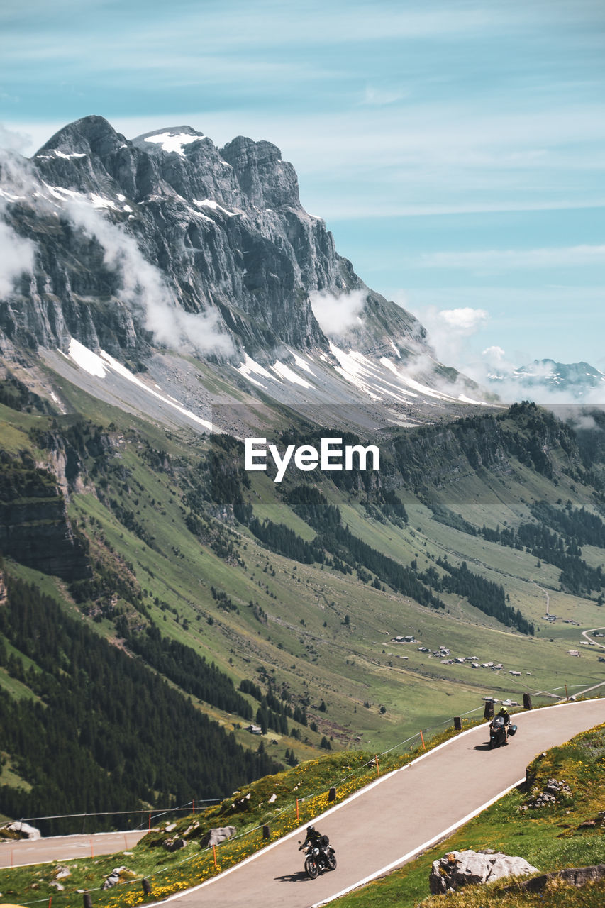 Scenic view of road by mountains against sky with motorcycle 