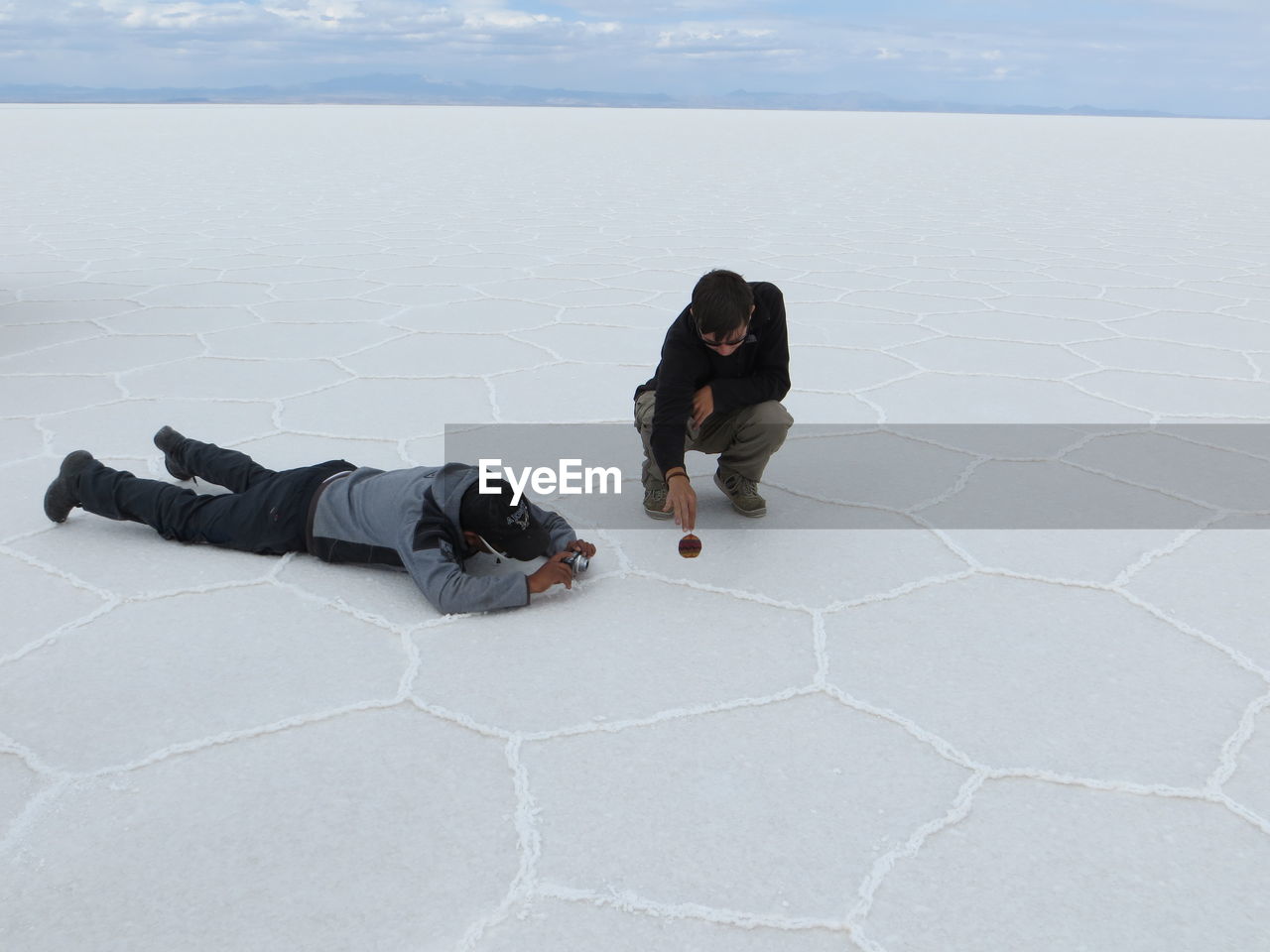 High angle view of 2 friends laying down and photographing 