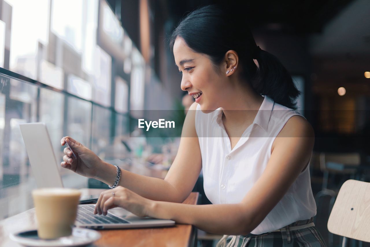 Woman holding credit card at cafe