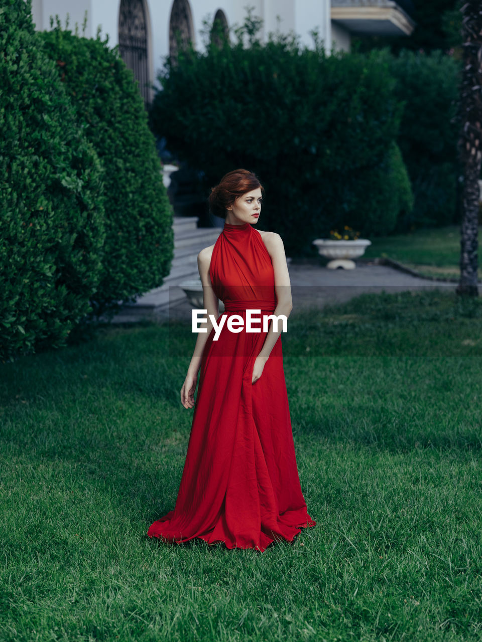 YOUNG WOMAN STANDING BY GRASS