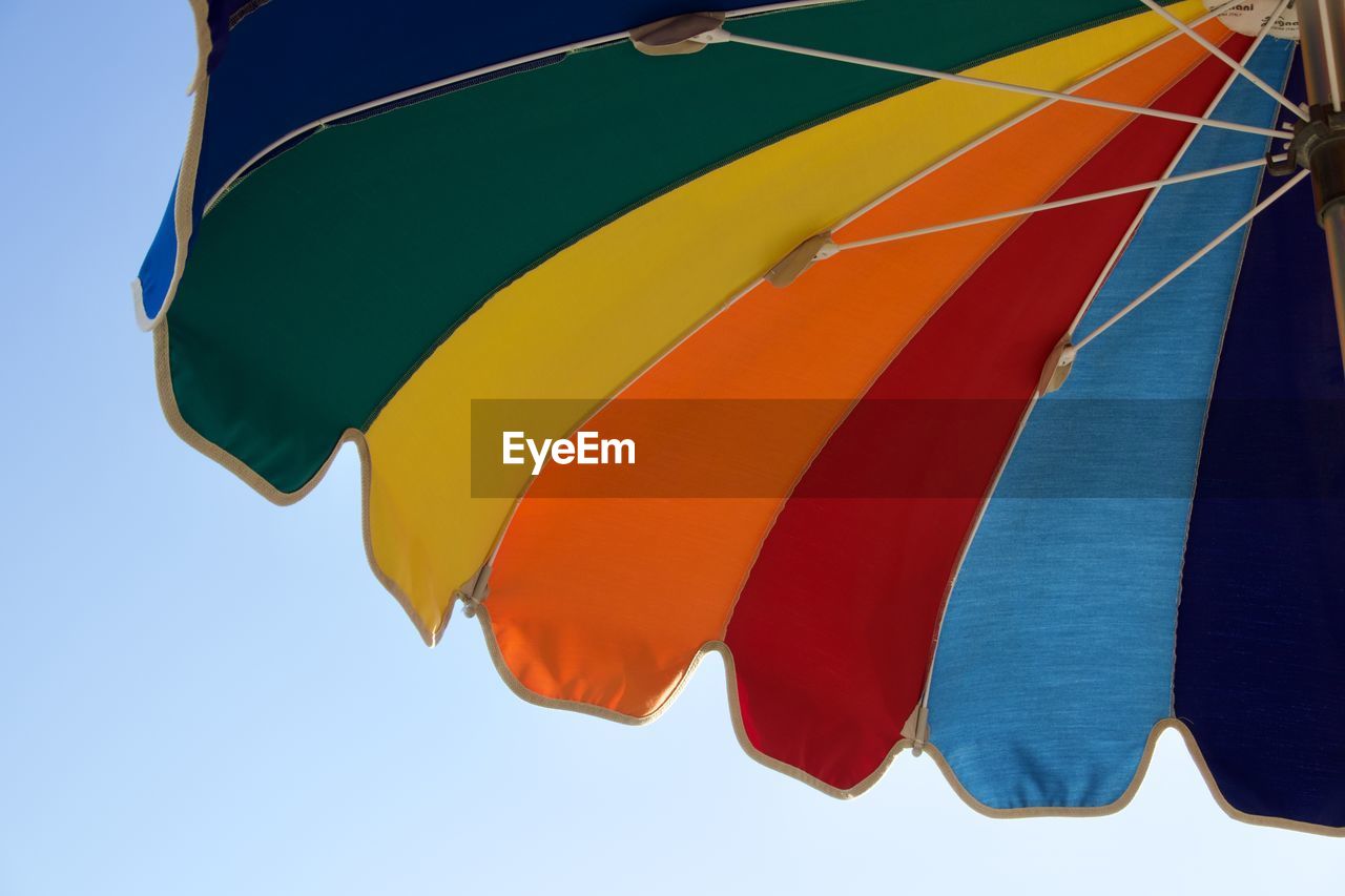 Low angle view of multi colored beach umbrella against clear sky