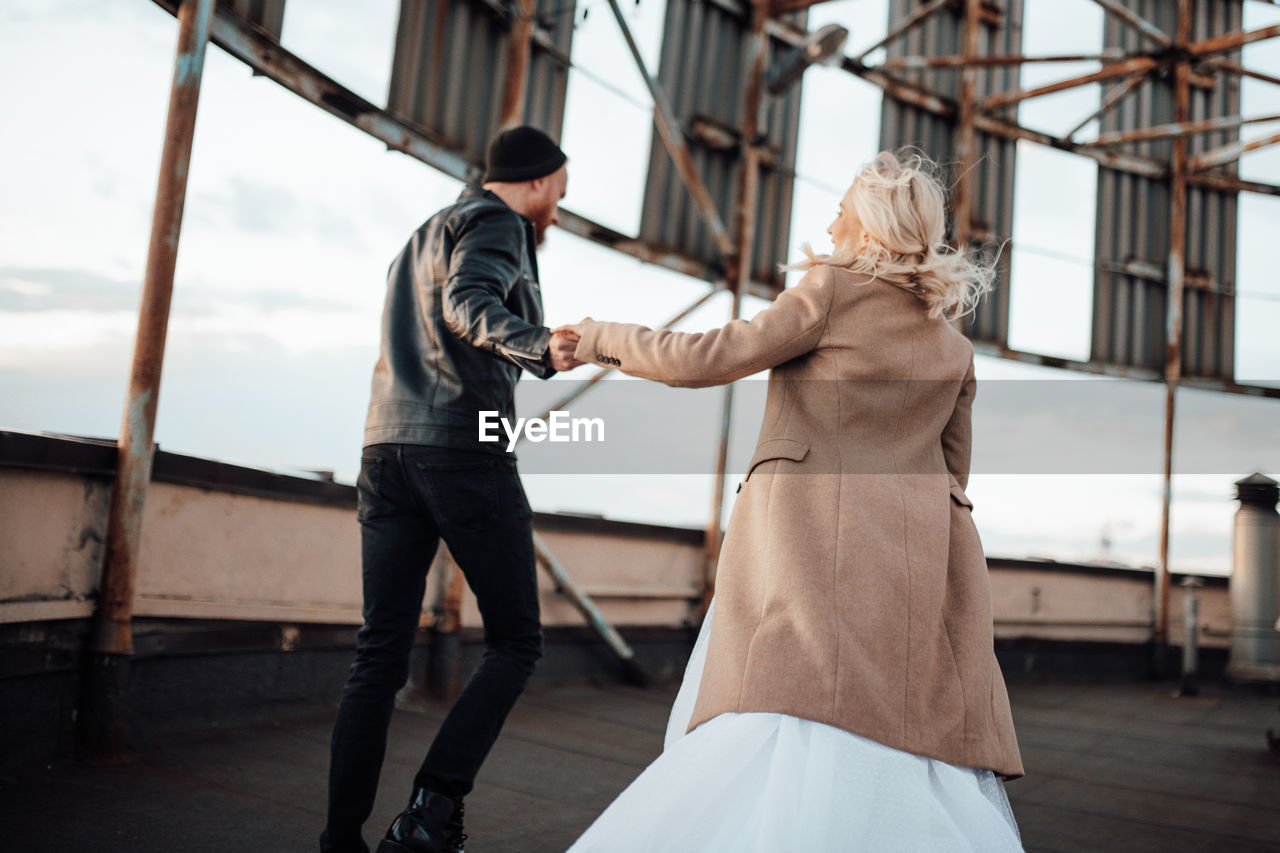 Rear view of couple standing on railing