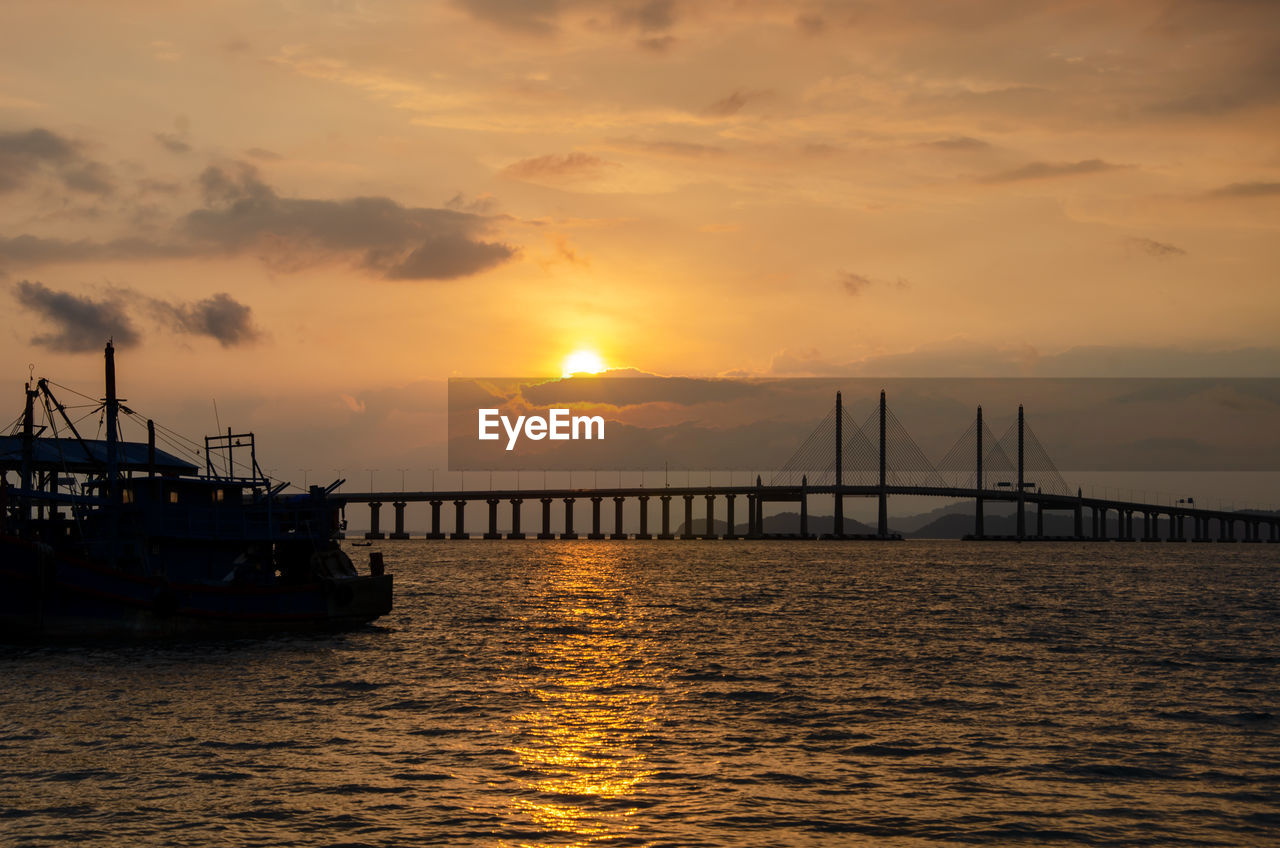 Bridge over sea against sky during sunset