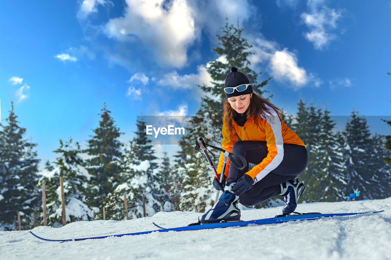Full length of woman wearing ski on snow against pine trees during winter