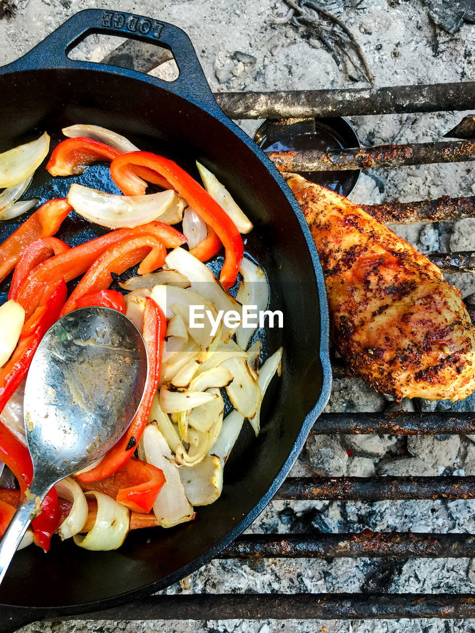 Vegetables in pan with chicken meat on barbeque grill