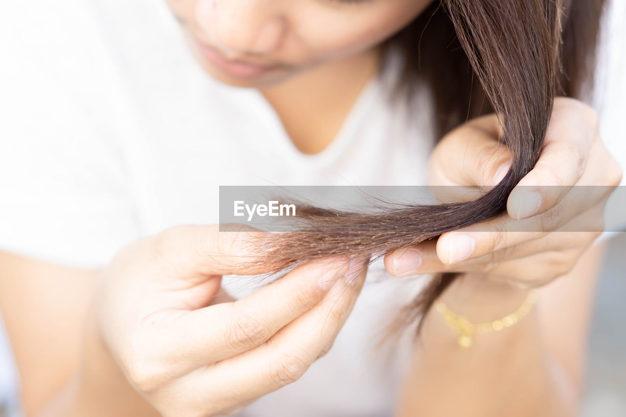 Midsection of woman showing damaged hair at home