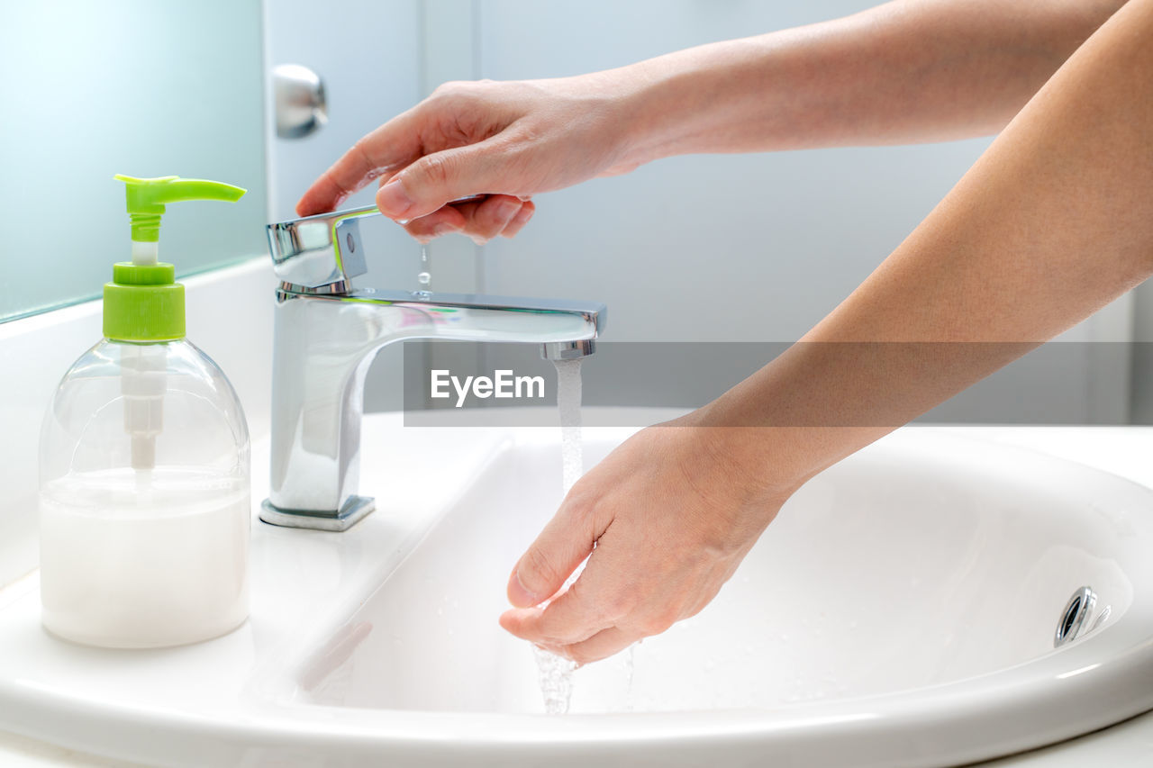 Cropped image of woman washing hands in sink