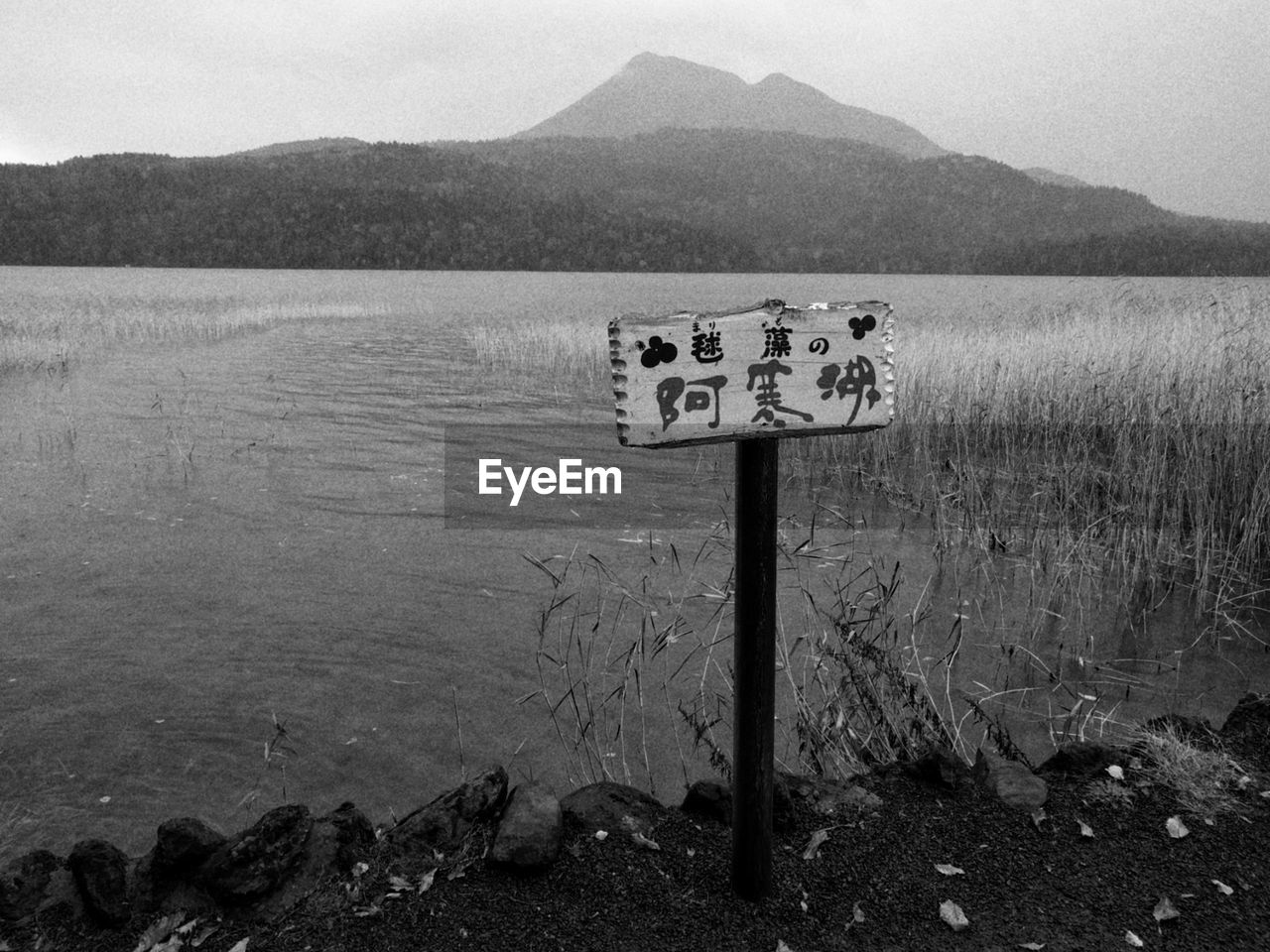 WARNING SIGN ON WOODEN POST IN LAKE