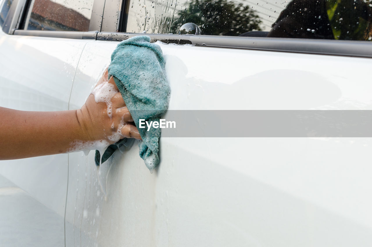 Cropped hand of woman washing car