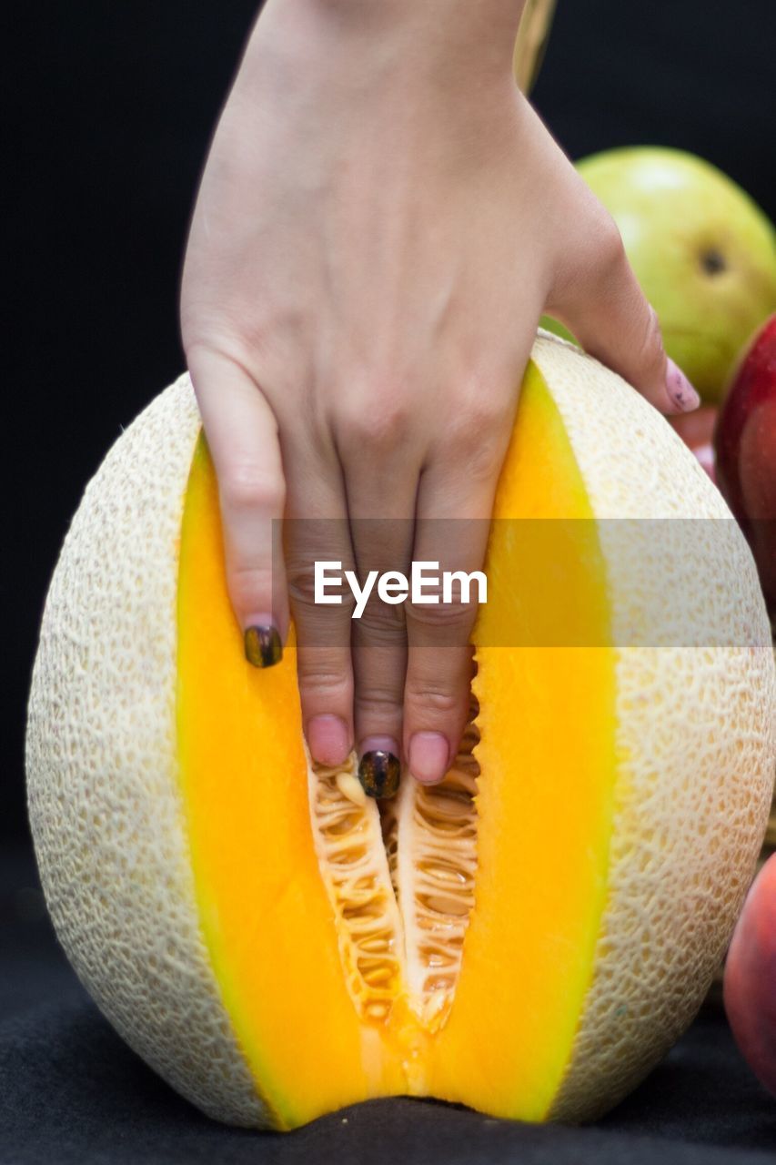 CLOSE-UP OF HAND HOLDING YELLOW FRUIT