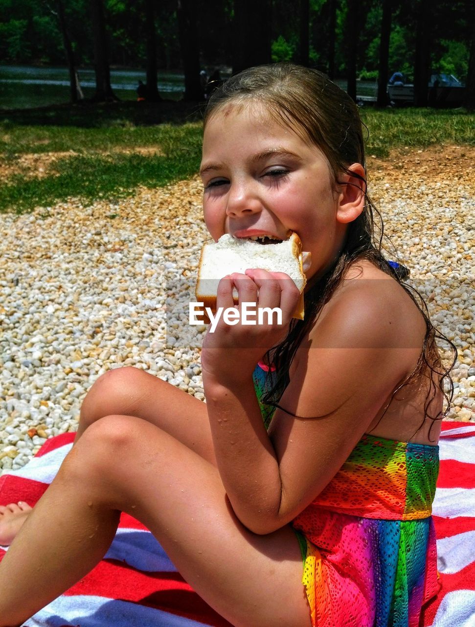 Portrait of girl eating food while sitting on beach