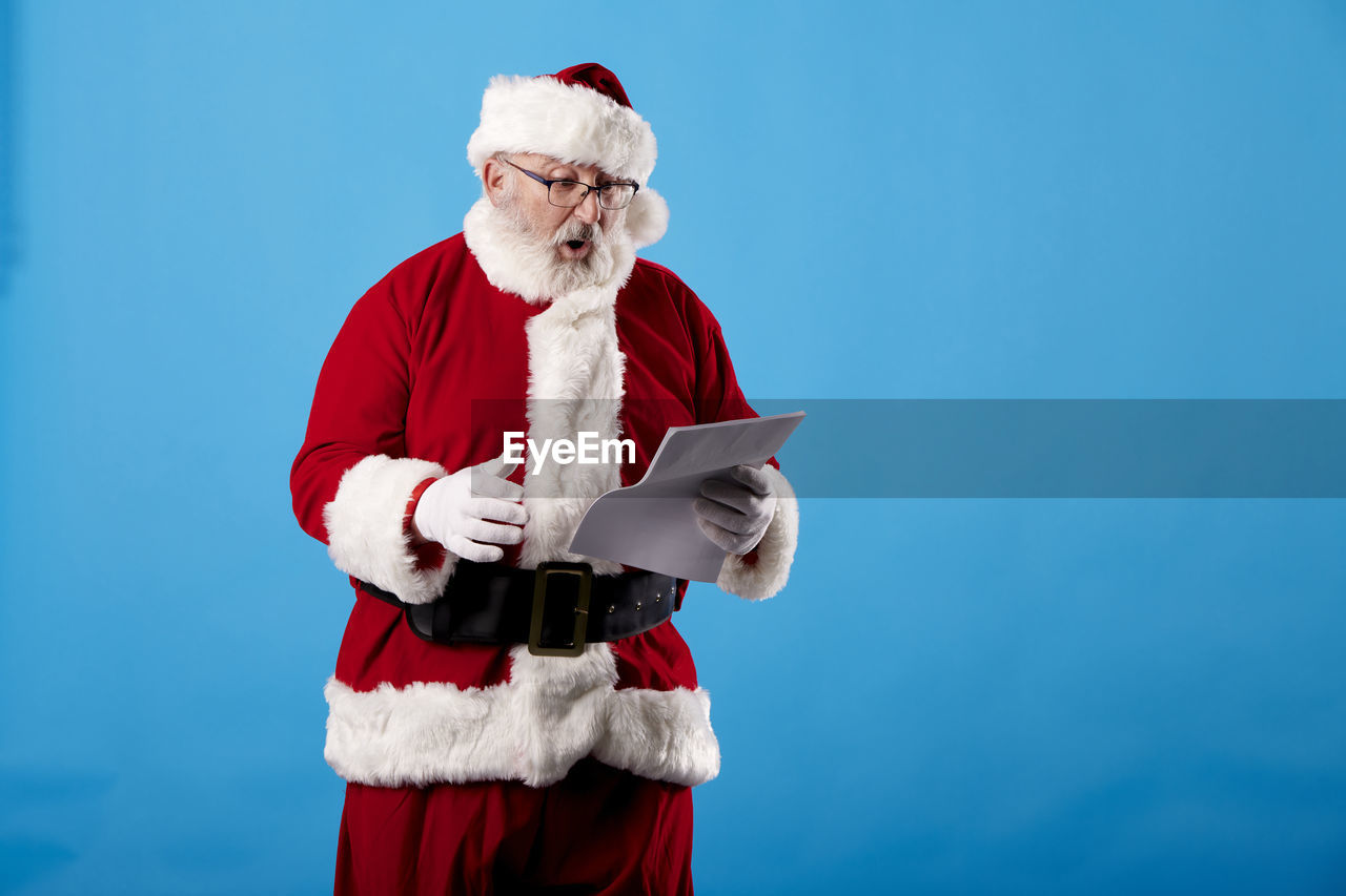 Santa claus reading a letter on blue background