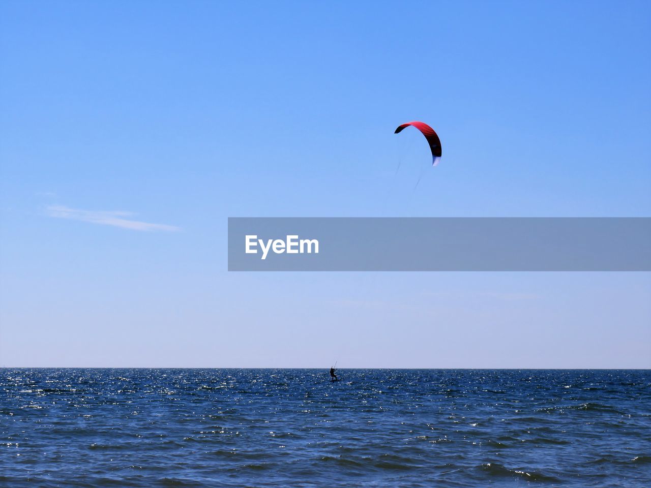 Kite flying over sea against blue sky